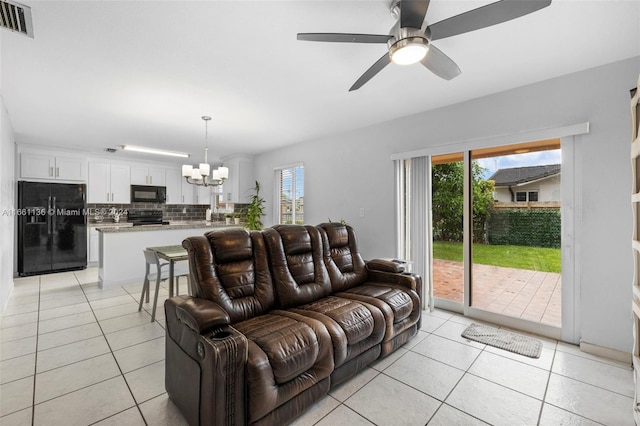 tiled living room with ceiling fan with notable chandelier