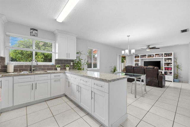 kitchen featuring light tile patterned flooring, sink, white cabinets, kitchen peninsula, and light stone countertops