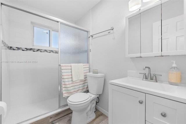 bathroom with wood-type flooring, walk in shower, vanity, and toilet