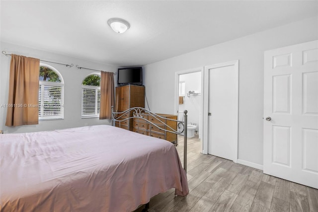 bedroom featuring ensuite bath and light hardwood / wood-style floors