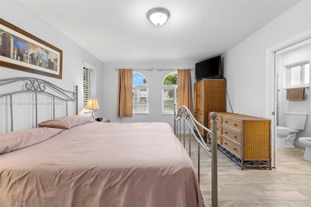 bedroom with light hardwood / wood-style floors and connected bathroom