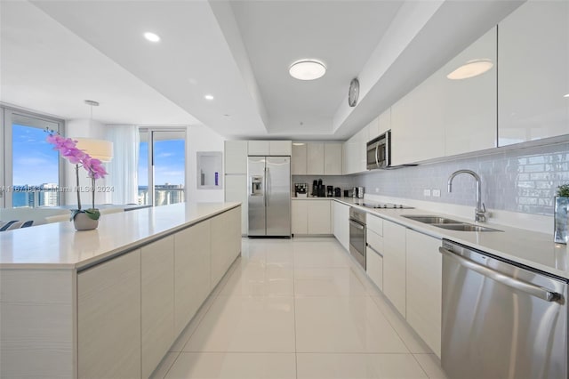 kitchen with a large island, sink, hanging light fixtures, decorative backsplash, and appliances with stainless steel finishes