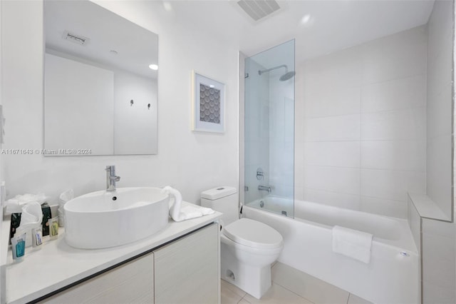 full bathroom with tile patterned flooring, tiled shower / bath combo, vanity, and toilet