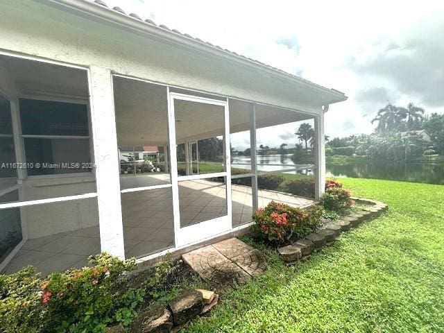 exterior space with a sunroom, a lawn, and a water view