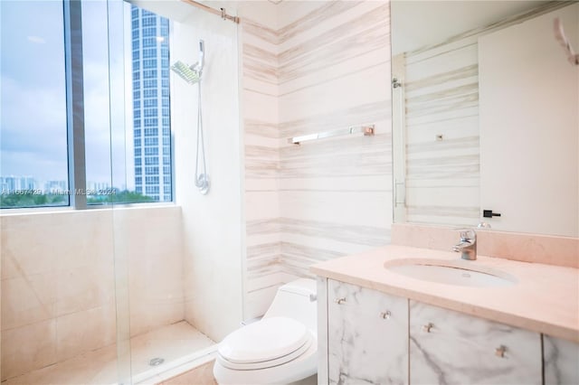 bathroom featuring a shower with door, vanity, and toilet