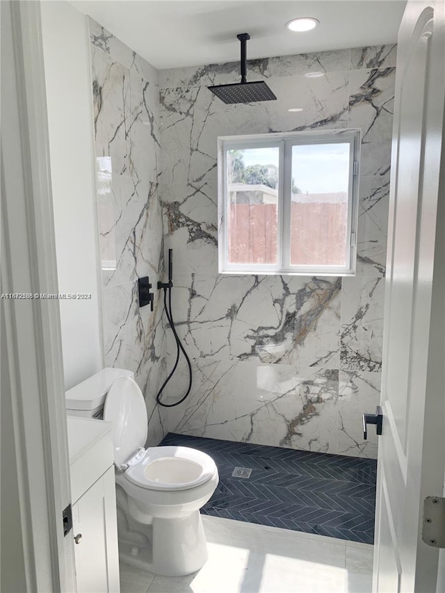 bathroom featuring vanity, a tile shower, and toilet