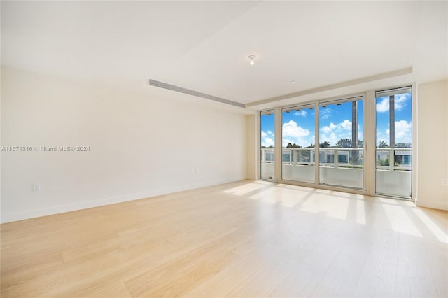 empty room with floor to ceiling windows and light hardwood / wood-style floors