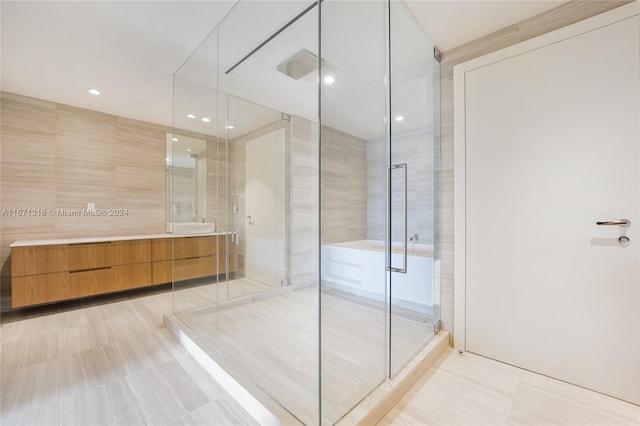 bathroom with tile walls, vanity, and a shower with shower door