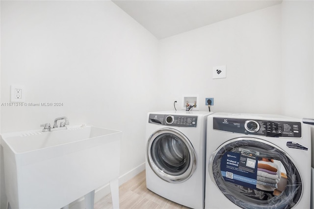 washroom with light hardwood / wood-style floors, independent washer and dryer, and sink