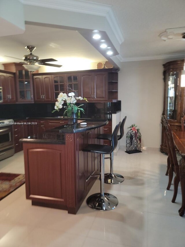 kitchen featuring range, crown molding, dark brown cabinets, and ceiling fan