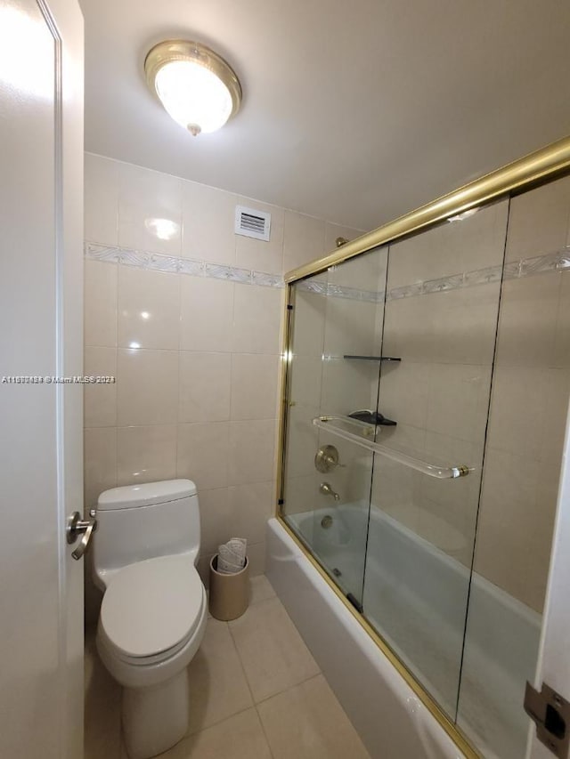 bathroom featuring tile walls, shower / bath combination with glass door, toilet, and tile patterned floors