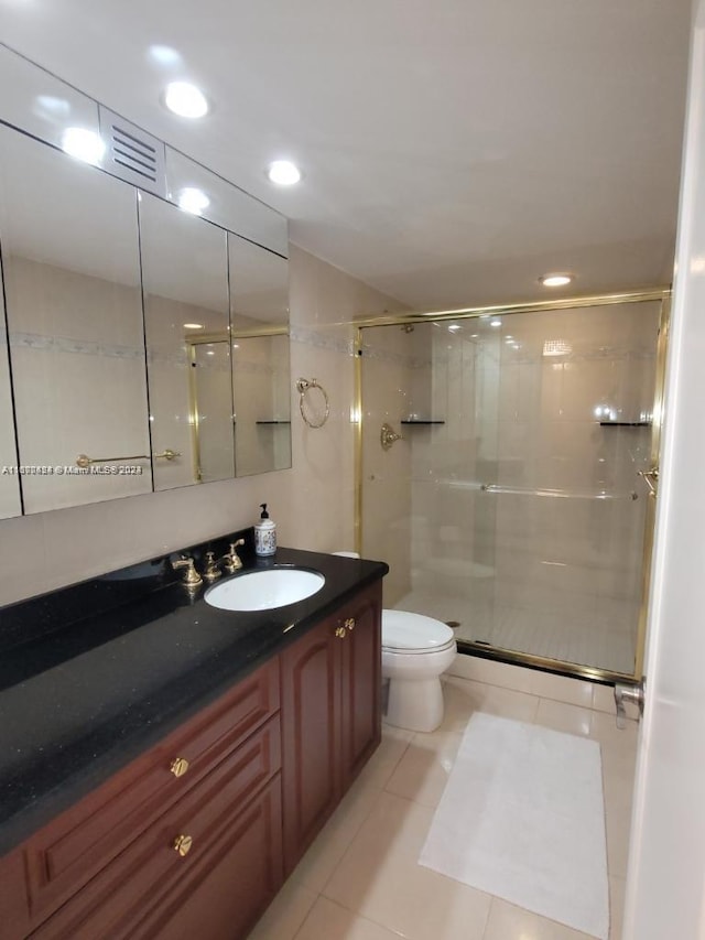 bathroom with vanity, a shower with shower door, toilet, and tile patterned flooring