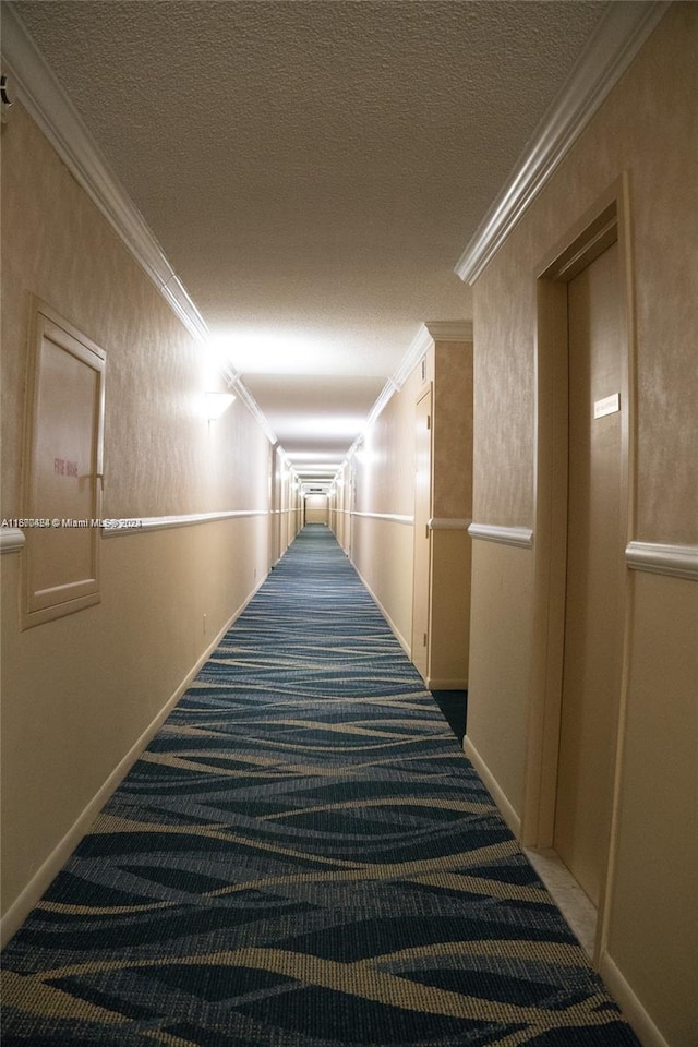 hallway featuring dark carpet, a textured ceiling, and crown molding