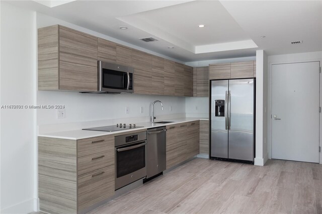 121 NE 34th St Unit 2806A, Miami, FL 33137 - kitchen featuring light countertops, a tray ceiling, a sink, and appliances with stainless steel finishes