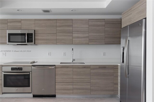 kitchen featuring appliances with stainless steel finishes, light tile patterned floors, and sink