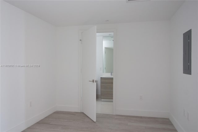 empty room with light hardwood / wood-style floors, electric panel, and sink