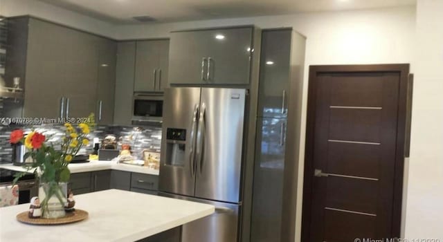 kitchen with gray cabinets, appliances with stainless steel finishes, and tasteful backsplash