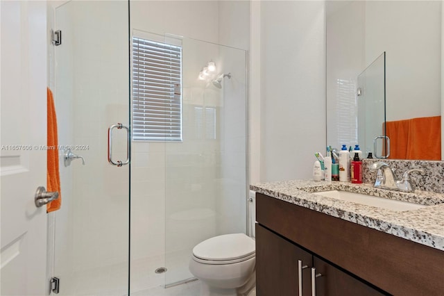 bathroom with a shower with shower door, vanity, and toilet