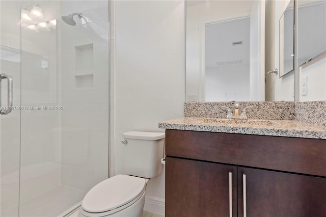 bathroom with a shower with door, vanity, and toilet