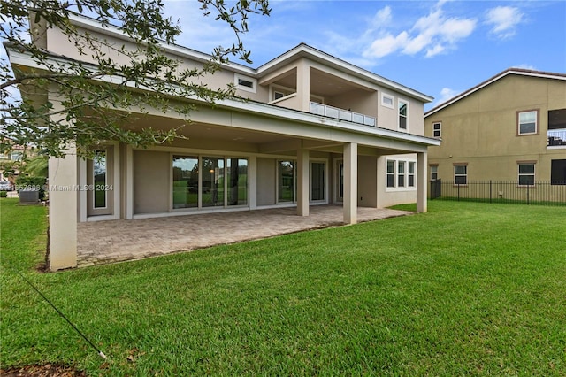 rear view of house with a lawn, a balcony, and a patio area