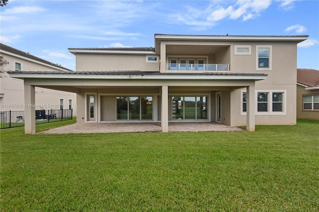 rear view of property featuring a balcony, a patio area, and a yard