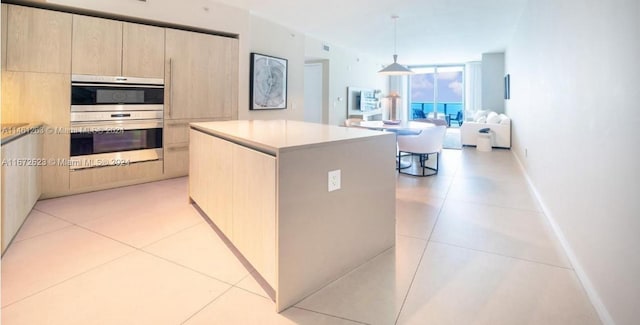 kitchen featuring pendant lighting, double oven, light brown cabinets, and a center island