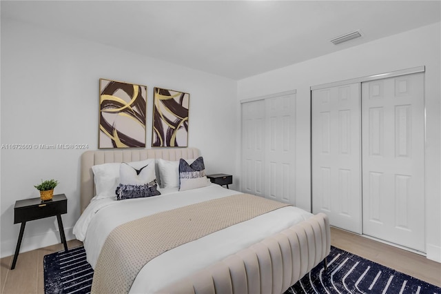 bedroom featuring light wood-type flooring and two closets