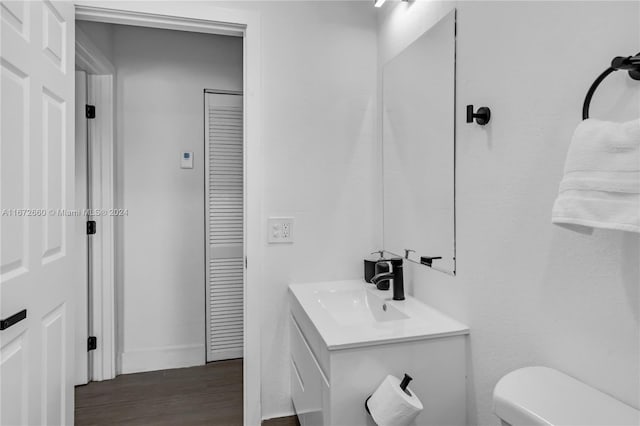 bathroom with wood-type flooring, vanity, and toilet