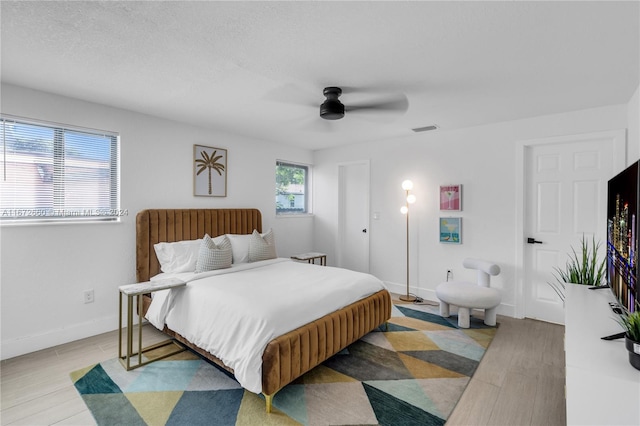 bedroom with ceiling fan, a textured ceiling, and light hardwood / wood-style flooring