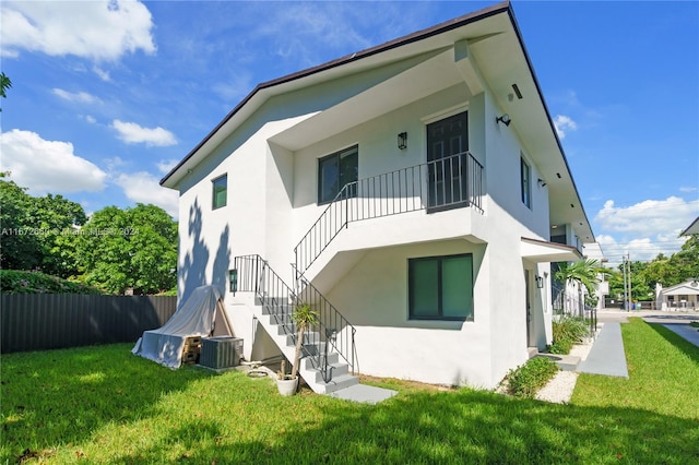 back of property with a yard and central AC unit