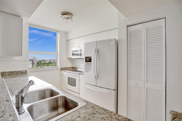 kitchen featuring white cabinetry, sink, light stone counters, and white appliances