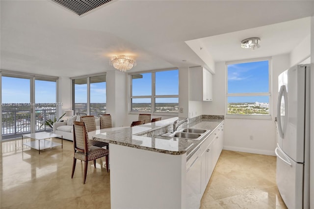 kitchen featuring kitchen peninsula, white appliances, white cabinetry, and sink