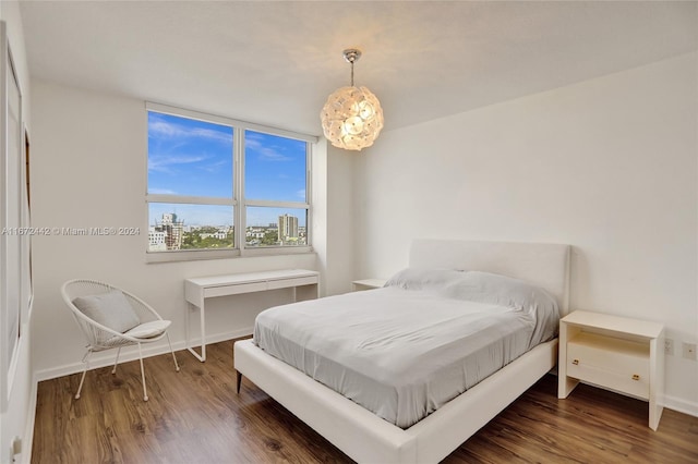 bedroom with a chandelier and dark wood-type flooring