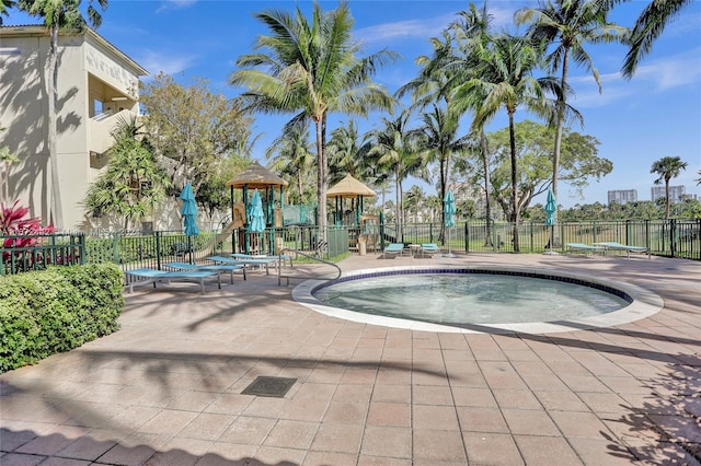 view of swimming pool with a playground and a hot tub