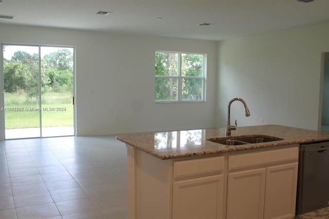 kitchen featuring light stone counters, light tile patterned flooring, sink, white cabinetry, and stainless steel dishwasher