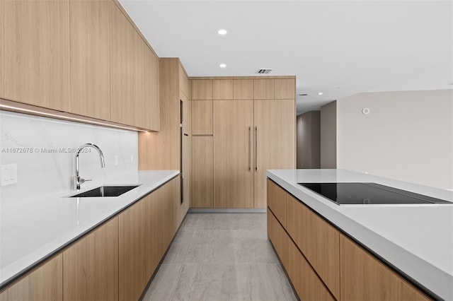 kitchen featuring black electric cooktop, light brown cabinetry, and sink