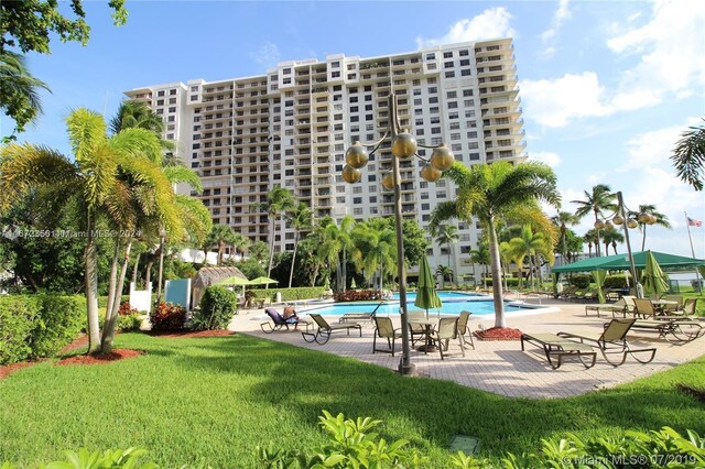 view of community featuring a swimming pool, a yard, and a patio