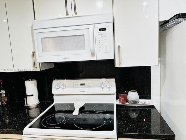 kitchen with white cabinets, dark stone counters, tasteful backsplash, and white appliances