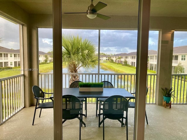 sunroom featuring ceiling fan and a water view