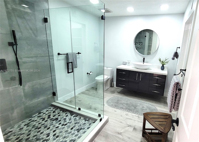 bathroom with walk in shower, vanity, toilet, and wood-type flooring