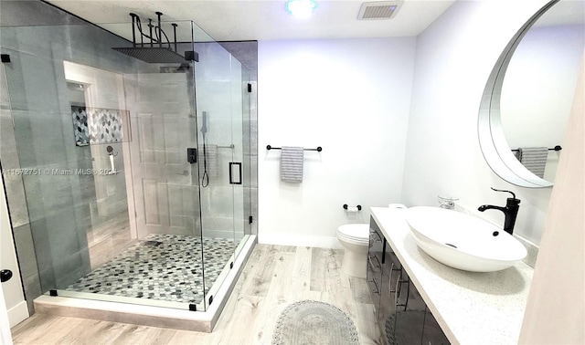 bathroom with hardwood / wood-style floors, vanity, toilet, and a shower with shower door