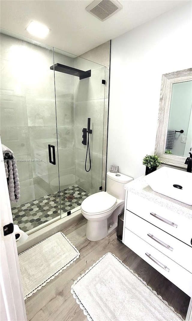 bathroom with hardwood / wood-style flooring, vanity, toilet, and an enclosed shower