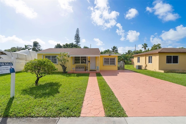 ranch-style home with stucco siding, driveway, central AC, and a front lawn