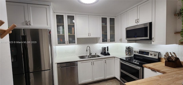 kitchen featuring decorative backsplash, white cabinets, appliances with stainless steel finishes, and a sink