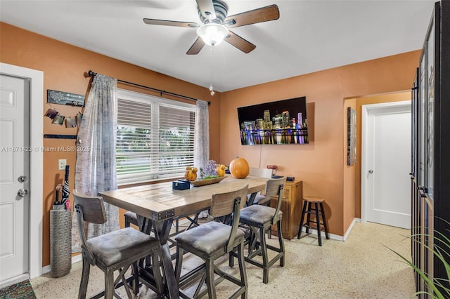 dining area featuring baseboards, light speckled floor, and a ceiling fan