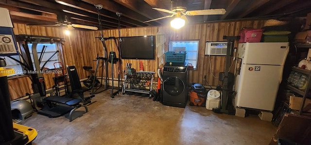 basement featuring a ceiling fan, wood walls, and freestanding refrigerator