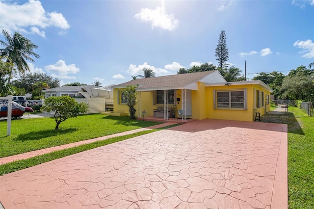 back of property with a yard, fence, and stucco siding