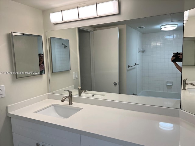 bathroom with tiled shower / bath combo and vanity