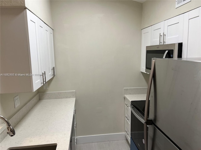 kitchen featuring light hardwood / wood-style flooring, appliances with stainless steel finishes, sink, and white cabinetry