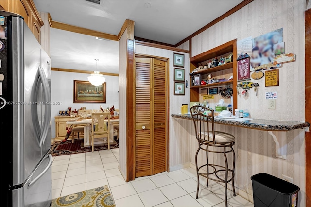 kitchen with a breakfast bar area, stainless steel refrigerator, light tile patterned floors, and decorative light fixtures